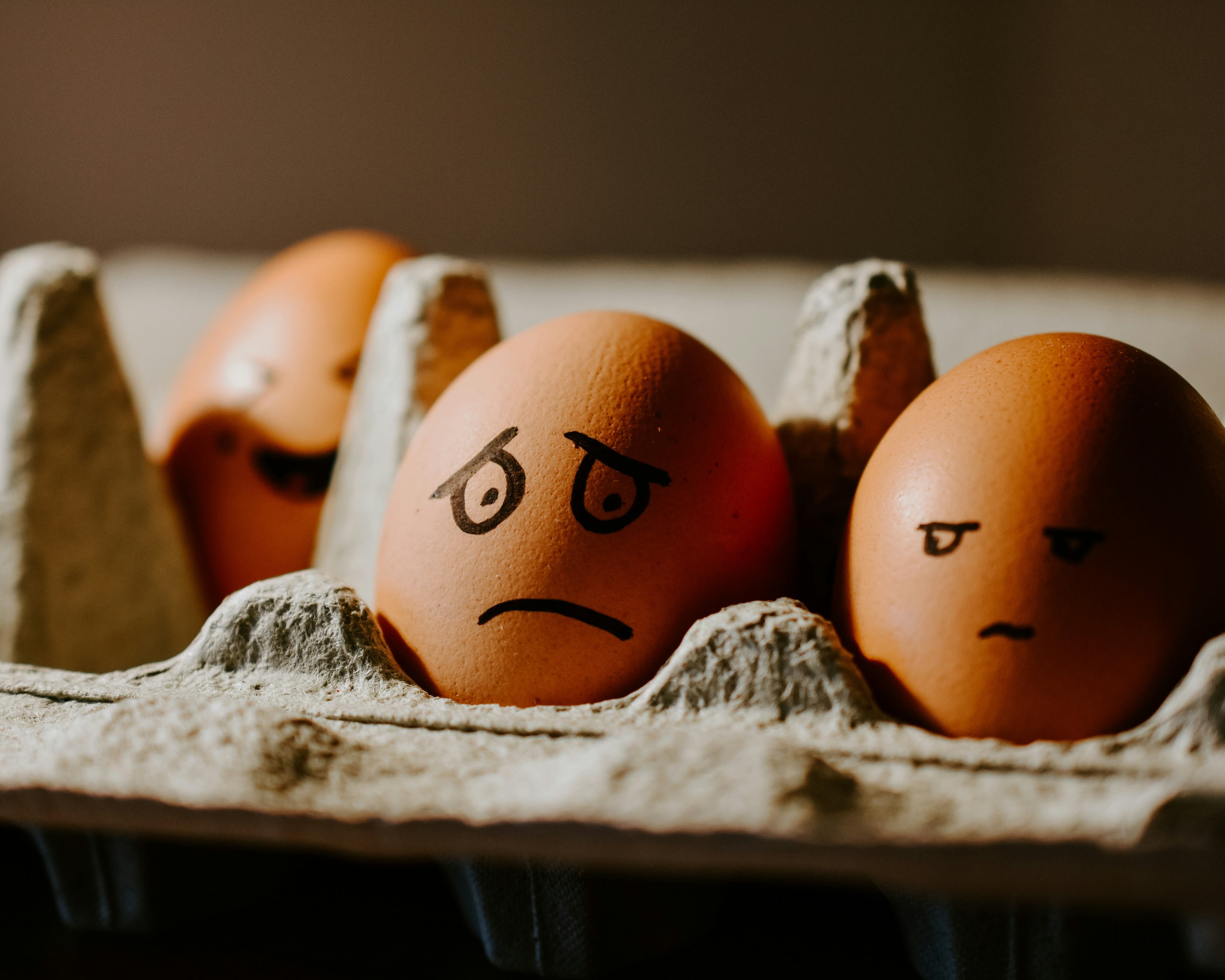 Ägg med målade ansiktsuttryck i äggkartong – symbol för oro över livsmedelssäkerhet när kyl och frys står utan el.