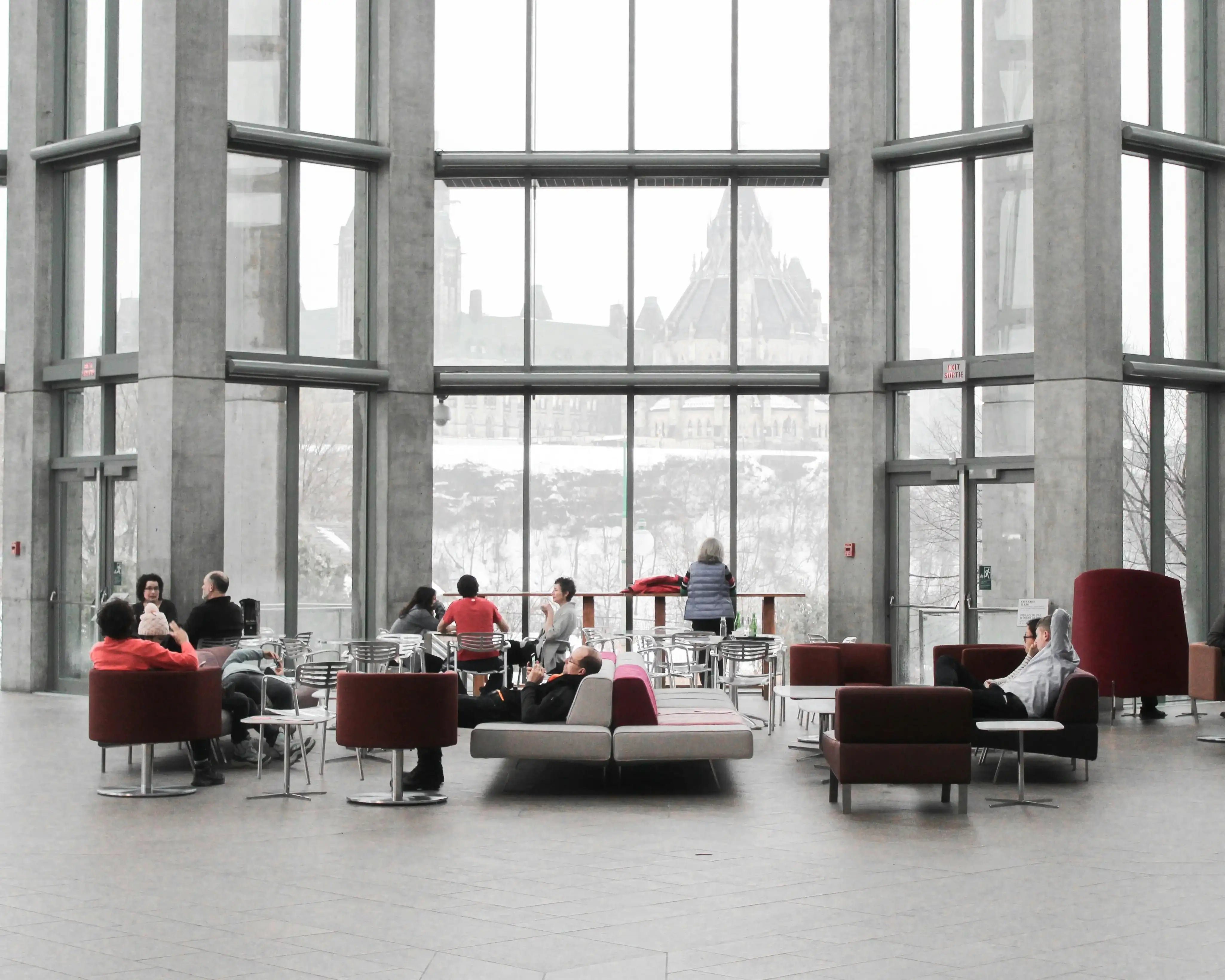  En rymlig inomhusmiljö med stora fönster och människor som sitter och umgås.