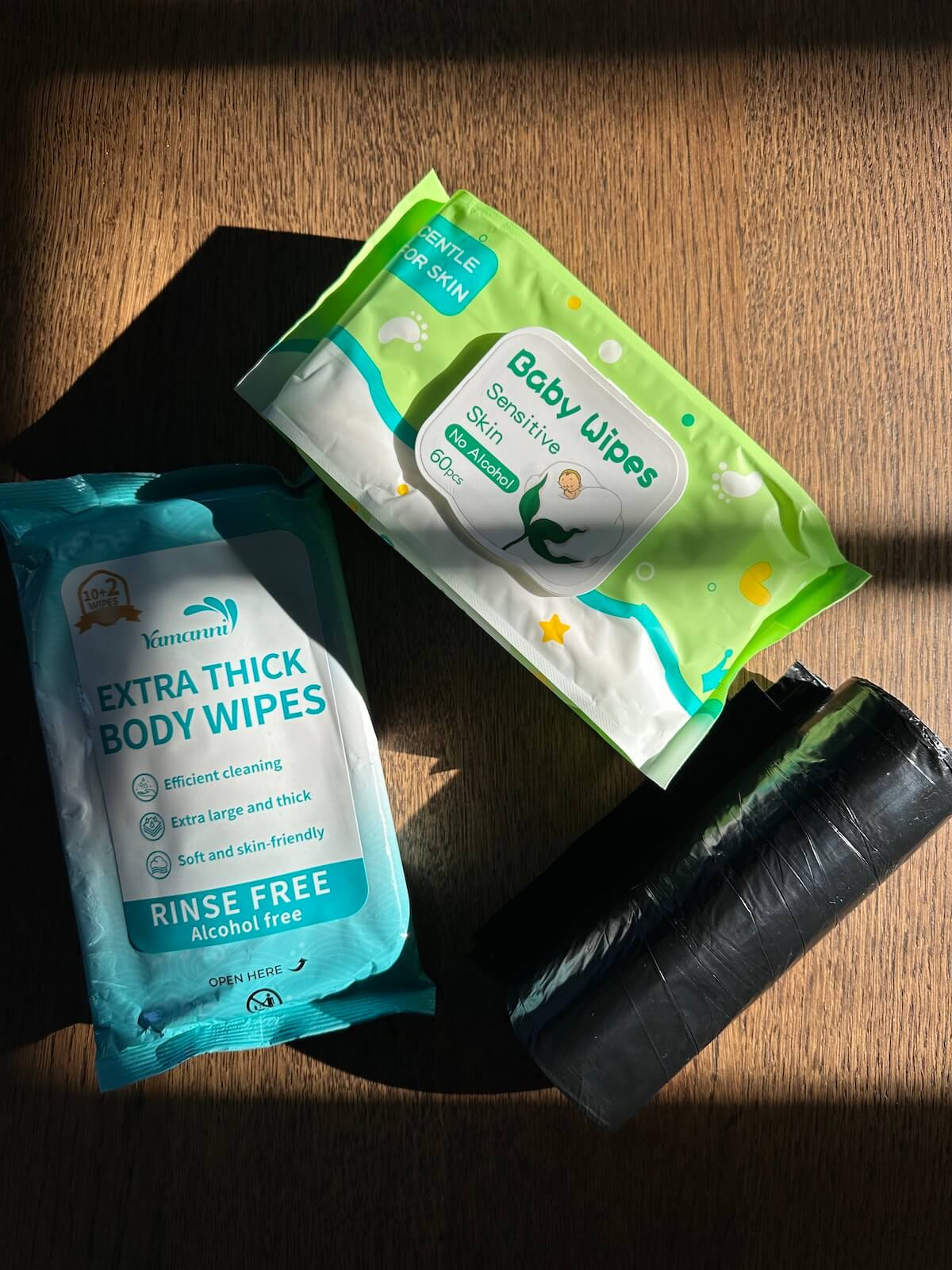 Två förpackningar med våtservetter – en för baby och en för kroppen – och en rulle med svarta soppåsar.